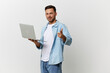 © SHOTPRIME STUDIO - Smiling handsome IT professional man in casual basic t-shirt point finger at camera hold laptop posing isolated on over white studio background copy space. Electronics repair. I choose you concept
