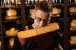 Handsome bearded cheese sommelier in fashion glasses holding and sniff limited gouda cheese. Snack tasty piece of cheese for appetizer.