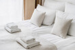 Fresh white bedclothes and towels on bed