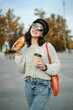 Woman in orange sweater with croissant and cup of coffee posing on cafe background 