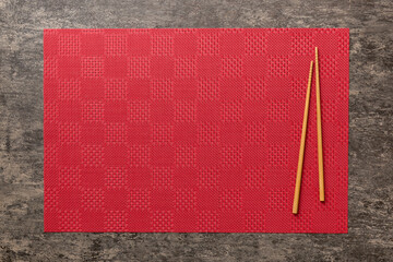 Wall Mural - Two chopsticks and bamboo mat on cement background. Top view, copy space