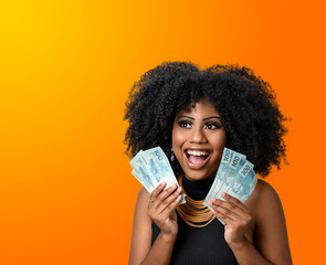 Wall Mural - woman holding money, young smiling woman holding Brazilian money, orange gradient background