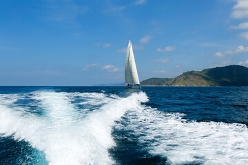 Wall Mural - Wake from motor boat with sailboat in background located in Phuket Island, Phuket, Thailand.