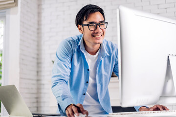 young smiling asian man using laptop computer working and study with document at home.young creative