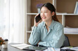 © amnaj - Asian businesswoman talking on the phone with customer in the office.