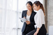 © David - Businesswoman executive is using a tablet in meeting discussion with another businesswoman or client in modern workplace office. People corporate Asian business people team concept.