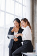 © David - Businesswoman executive is using a tablet in meeting discussion with another businesswoman or client in modern workplace office. People corporate Asian business people team concept.