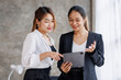 © David - Businesswoman executive is using a tablet in meeting discussion with another businesswoman or client in modern workplace office. People corporate Asian business people team concept.
