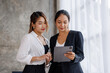 © David - Businesswoman executive is using a tablet in meeting discussion with another businesswoman or client in modern workplace office. People corporate Asian business people team concept.