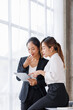 © David - Businesswoman executive is using a tablet in meeting discussion with another businesswoman or client in modern workplace office. People corporate Asian business people team concept.