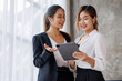 © David - Businesswoman executive is using a tablet in meeting discussion with another businesswoman or client in modern workplace office. People corporate Asian business people team concept.