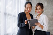 © David - Businesswoman executive is using a tablet in meeting discussion with another businesswoman or client in modern workplace office. People corporate Asian business people team concept.