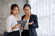 © David - Businesswoman executive is using a tablet in meeting discussion with another businesswoman or client in modern workplace office. People corporate Asian business people team concept.