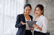 © David - Businesswoman executive is using a tablet in meeting discussion with another businesswoman or client in modern workplace office. People corporate Asian business people team concept.