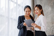 © David - Businesswoman executive is using a tablet in meeting discussion with another businesswoman or client in modern workplace office. People corporate Asian business people team concept.