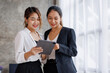 © David - Businesswoman executive is using a tablet in meeting discussion with another businesswoman or client in modern workplace office. People corporate Asian business people team concept.