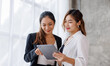 © David - Businesswoman executive is using a tablet in meeting discussion with another businesswoman or client in modern workplace office. People corporate Asian business people team concept.