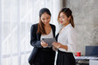 © David - Businesswoman executive is using a tablet in meeting discussion with another businesswoman or client in modern workplace office. People corporate Asian business people team concept.