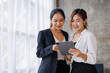 © David - Businesswoman executive is using a tablet in meeting discussion with another businesswoman or client in modern workplace office. People corporate Asian business people team concept.