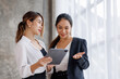 © David - Businesswoman executive is using a tablet in meeting discussion with another businesswoman or client in modern workplace office. People corporate Asian business people team concept.