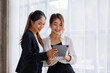 © David - Businesswoman executive is using a tablet in meeting discussion with another businesswoman or client in modern workplace office. People corporate Asian business people team concept.