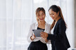 © David - Businesswoman executive is using a tablet in meeting discussion with another businesswoman or client in modern workplace office. People corporate Asian business people team concept.