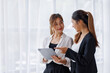 © David - Businesswoman executive is using a tablet in meeting discussion with another businesswoman or client in modern workplace office. People corporate Asian business people team concept.