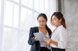 © David - Businesswoman executive is using a tablet in meeting discussion with another businesswoman or client in modern workplace office. People corporate Asian business people team concept.