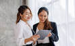 © David - Businesswoman executive is using a tablet in meeting discussion with another businesswoman or client in modern workplace office. People corporate Asian business people team concept.