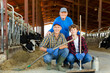 © JackF - Successful elderly dairy farm owner with son and teen grandson posing together while working in stall with cows. Three generations of farming dynasty
