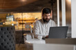 © Andrii Lysenko - Young bearded man working in cafe using laptop, freelancer work man with pc in coffee shop