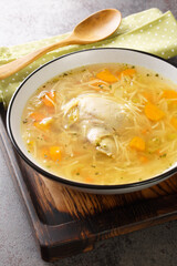 Wall Mural - Chicken broth with noodles and vegetables close-up in a plate on a wooden tray. Vertical