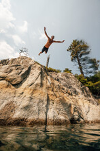 Man Jumping From Cliff Into Lake