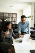 © JustLife - Colleagues in office. Businesswoman and businessman discussing work in office..