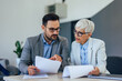 © bnenin - Close up of two business colleagues, holding and reading some papers.