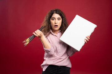 Young artist posing with paintbrushes and canvas