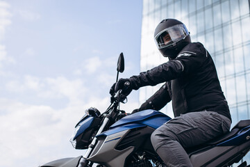 Handsome motorcyclist on his moto riding in the city