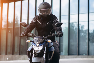 Handsome motorcyclist on his moto riding in the city