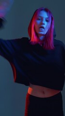 vertical video. rap dance. hip hop culture. urban style. neon light girl in hoodie breakdancing in r