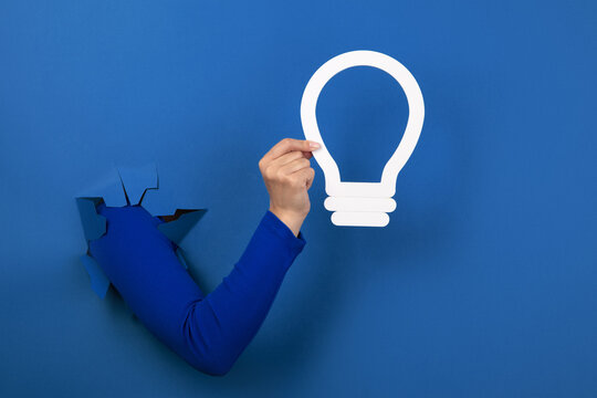hand holding light bulb over blue background