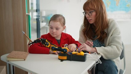 Wall Mural - young teacher is private tutoring little student with down syndrome during robotics class at school.
