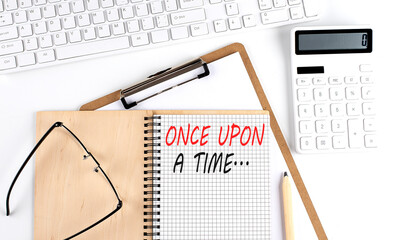 Notebook with the word ONCE UPON A TIME with keyboard and calculator on the white background