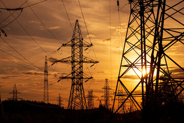 High voltage pole on silhouette summer sunset background.