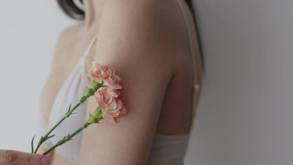 Wall Mural - Portrait of young beautiful woman holding flower over grey background.