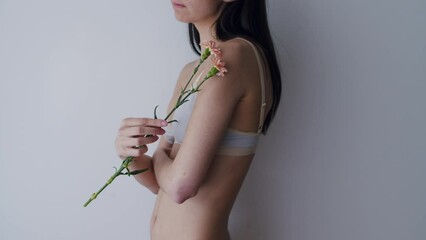 Wall Mural - Portrait of young beautiful woman holding flower over grey background.