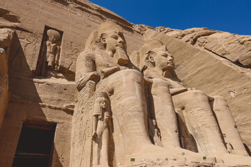 The main view of an Entrance to the Great Temple at Abu Simbel with Ancient Colossal statues of Ramesses II, seated on a throne and wearing the double crown of Upper and Lower Egypt