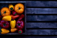 Top View Of Red And Orange Organic Tomatoes With Peppers Inside Old Wooden Box On Wooden Background