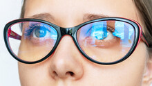 Portrait Of A Young Caucasian Woman With Stylish Female Glasses For Working At A Computer With A Blue Filter Lenses Isolated On A White Background. Anti Blue Light And Rays. Eye Protection