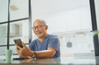 © eggeeggjiew - Happy Senior mature male sitting using smartphone at home, Leisure, Active Lifestyle