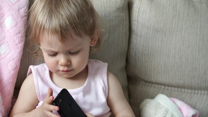 close up of little baby girl plays phone. happy child surfing internet, touches digital phone with f
